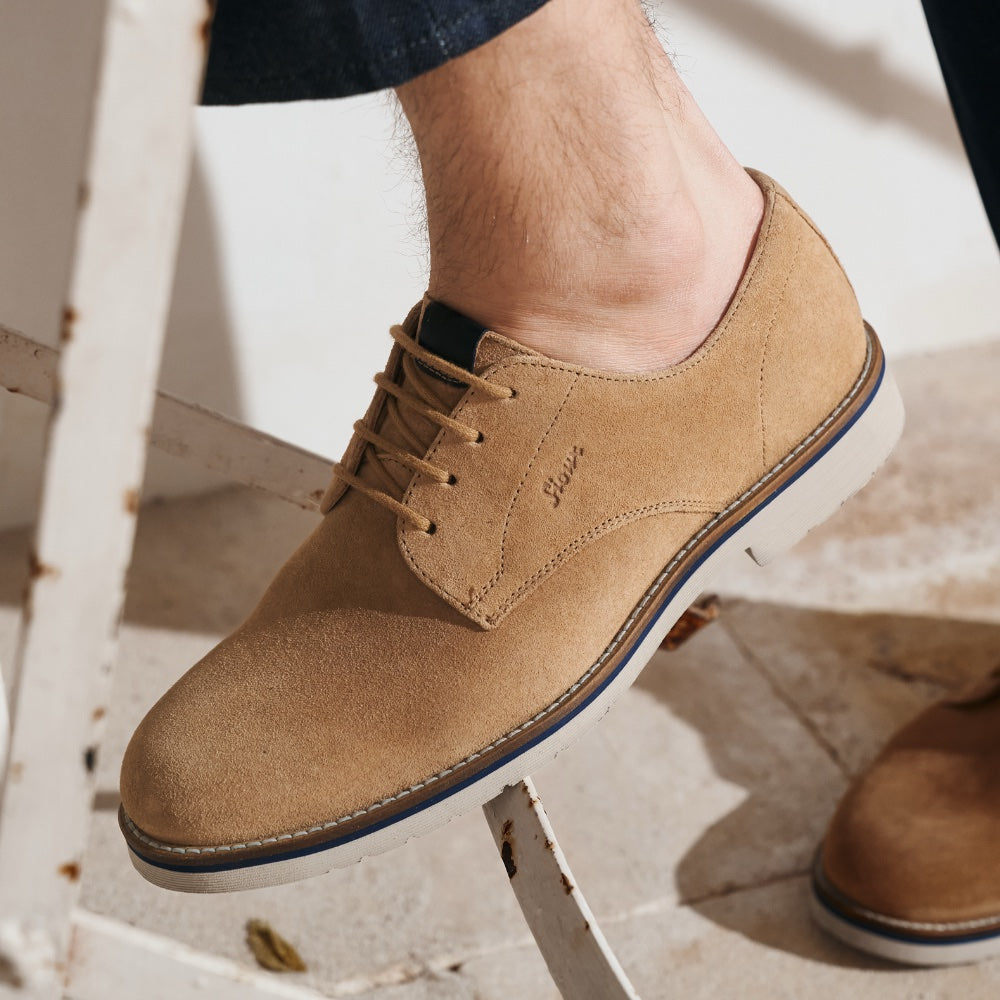 Tan suede leather shoe on a white stool with a neutral background