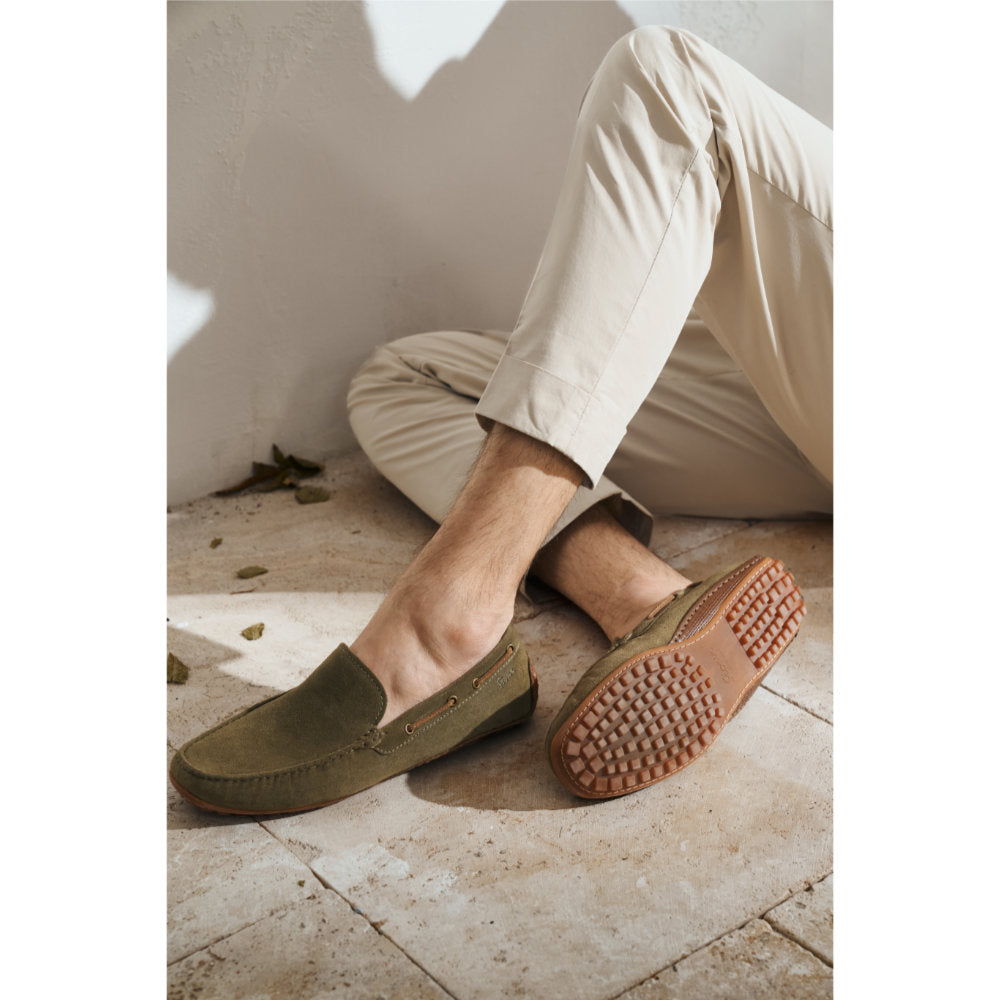 Worn lifestyle image of green calf suede Callimo moccasin for men showing distinctive color blocking and lightweight rubber sole curve at the heel ideal for car drivers